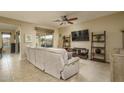 Cozy living room with tan carpet, tan walls, a ceiling fan and a sliding door to the backyard at 9547 W Chama Dr, Peoria, AZ 85383