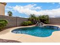 Inviting backyard oasis with a sparkling pool, rock waterfall feature, and lush tropical landscaping at 17358 N 185Th Ln, Surprise, AZ 85374