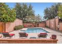 Serene pool area featuring a spa, red lounge chairs, lush greenery, and brick surround at 3002 N 32Nd St # 13, Phoenix, AZ 85018