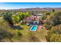 Expansive aerial view of home with refreshing pool, lush lawn, desert landscape, and serene mountain backdrop at 3264 E Vineyard Rd, Phoenix, AZ 85042