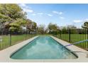 Beautiful in-ground pool surrounded by lush greenery and a secure fence, perfect for relaxation at 3264 E Vineyard Rd, Phoenix, AZ 85042
