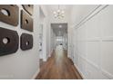 Long hallway features hardwood floors, modern light fixture, decorative wall panels, and artistic wall decor at 440 E Aurora Dr, San Tan Valley, AZ 85140