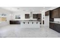 Spacious kitchen featuring dark wood cabinets, white marble floors, a large island and stainless steel appliances at 5710 N 84Th Ave, Glendale, AZ 85305