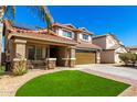 Two-story home featuring a charming front porch, two-car garage, tile roof, and low-maintenance desert landscaping at 650 E Daniella E Dr, San Tan Valley, AZ 85140