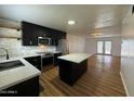 Modern kitchen features sleek black cabinets, stainless steel appliances, and a spacious island with quartz countertops at 7129 W Meadowbrook Ave, Phoenix, AZ 85033