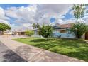 Street view of a light-blue single-story home featuring a green lawn and mature landscaping at 12607 N 25Th Ave, Phoenix, AZ 85029