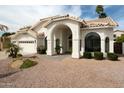 Elegant white home with arched entryway, well-maintained landscaping, and a three-car garage at 6232 E Monte Cristo Ave, Scottsdale, AZ 85254