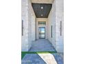 Covered entrance featuring stone columns and modern lighting fixtures framing a sleek glass door at 7261 E Via Dona Rd, Scottsdale, AZ 85266