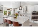 Modern kitchen with a large center island, pendant lighting, stainless steel appliances, and white cabinetry at 7435 E Corrine Rd, Scottsdale, AZ 85260