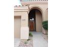 Inviting arched entryway with a wood front door and desert landscaping accents at 13487 E Gold Dust Ave, Scottsdale, AZ 85259