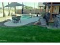 Lush backyard featuring a sparkling pool, outdoor dining area, and a cozy bar under a pergola at 1353 S Western Skies Dr, Gilbert, AZ 85296