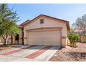 Tan single-story home featuring a two-car garage and brick-lined driveway on a sunny day at 219 E Valley View Dr, Phoenix, AZ 85042