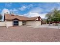 Well-kept single-story residence with a two-car garage and a lengthy driveway on a sunny, cloud-filled day at 7414 W Tuckey Ln, Glendale, AZ 85303