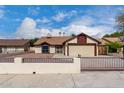 Beige single-story home with a two-car garage, desert landscaping, and a gated front yard at 7414 W Tuckey Ln, Glendale, AZ 85303