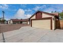 Beige two-car garage attached to a single-story home with a long driveway and desert landscaping at 7414 W Tuckey Ln, Glendale, AZ 85303