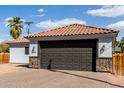 Close up of attached garage with dark door, red tile roof and stone veneer accents under blue sky at 7715 N 23Rd Ave, Phoenix, AZ 85021