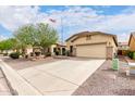 Tan single-story home featuring a two-car garage, desert landscaping, and a large driveway at 535 E Yellow Wood Ave, San Tan Valley, AZ 85140