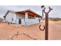 Exterior view of home with covered porch, rock features, and desert surroundings at 7209 N Maple St, Maricopa, AZ 85139