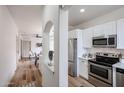 Bright kitchen featuring stainless steel appliances, white cabinetry, and modern finishes, and hardwood flooring at 859 S Bristol --, Mesa, AZ 85208