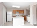 Well-lit kitchen featuring white appliances, a white island, and wooden cabinets for ample storage space at 13646 W Fargo Dr, Surprise, AZ 85374