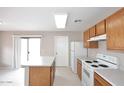 Bright kitchen with white appliances, wooden cabinets, and a center island with a white countertop at 13646 W Fargo Dr, Surprise, AZ 85374