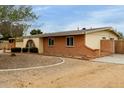 Single-story home with a gravel front yard featuring an arched entry gate at 3212 W Paradise Dr, Phoenix, AZ 85029