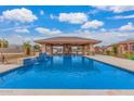 Resort-style pool featuring a covered outdoor living space with bar and waterfall features at 3718 N Briere Ct, Buckeye, AZ 85396