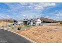 Wide shot showcasing the home's bright white facade, minimalist landscaping and serene desert surroundings at 6645 N Paint Ln, Casa Grande, AZ 85194