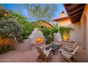 Cozy outdoor patio featuring a fireplace, comfortable seating, and lush landscaping at 10561 E Addy Way, Scottsdale, AZ 85262
