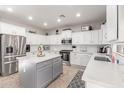 Modern kitchen boasts white cabinets, stainless steel appliances, a gray island, and tile backsplash at 11106 E Serafina Ave, Mesa, AZ 85212