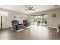 Cozy living room with wood-look tile flooring, ceiling fan, and sliding glass doors to the backyard at 13603 W Remuda Dr, Peoria, AZ 85383