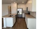 Modern kitchen featuring white cabinets, stainless steel appliances, a large island, and hardwood floors at 25156 W Wayland Dr, Buckeye, AZ 85326
