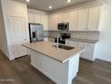 Bright kitchen featuring white cabinets, stainless steel appliances, a large island, and hardwood floors at 25156 W Wayland Dr, Buckeye, AZ 85326