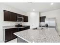 A modern kitchen is showcased with granite countertops, stainless steel appliances, and dark cabinets at 35569 N Breezy Ln, San Tan Valley, AZ 85140