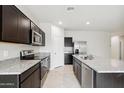 Beautiful kitchen featuring stainless steel appliances, granite countertops, dark cabinetry, and plenty of storage at 35569 N Breezy Ln, San Tan Valley, AZ 85140
