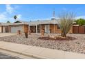 Inviting single-story home showcases xeriscaping, covered entry, and a brick facade with a two-car garage at 4432 E Carmel Ave, Mesa, AZ 85206