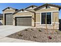 Beautiful home featuring a three-car garage, beige stucco, stone accents, and well-kept gravel landscaping at 4946 W Weeping Willow Way, Laveen, AZ 85339