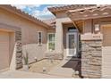Inviting front entrance featuring a decorative glass door, stone accents and desert landscaping at 8004 W Robin Ln, Peoria, AZ 85383