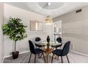 Cozy dining area with modern light fixture, glass table, and comfortable seating at 10547 W Coggins Dr, Sun City, AZ 85351