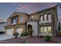 Two-story home features a distinctive architecture, desert landscaping, and a welcoming arched entryway at 12910 W Tuckey Ln, Glendale, AZ 85307