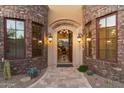 Elegant home entryway with stone accents, an arched doorway, and desert landscaping at 15956 E Tombstone Trl, Fountain Hills, AZ 85268