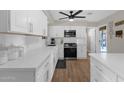 Well-lit kitchen showcases white countertops and cabinets, stainless steel appliances, and elegant wood-look flooring at 1715 W Carol Ave, Mesa, AZ 85202