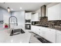 Modern kitchen featuring white cabinetry, stainless steel appliances, granite countertops, and mosaic backsplash at 17545 W Lilac St, Goodyear, AZ 85338