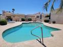 Community pool with clear water, lounge chairs, tables and sun umbrellas surrounded by lush landscaping at 2167 E Aspen Dr, Tempe, AZ 85282