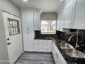 Well-lit kitchen with white cabinets, dark granite counters, stainless steel sink, and modern fixtures at 2945 N 19Th Ave # 78, Phoenix, AZ 85015