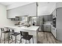 Eat-in kitchen featuring modern gray cabinets, stainless steel appliances, and stylish breakfast bar at 4129 W Caron St, Phoenix, AZ 85051