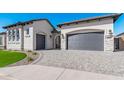 Beautiful home with gray doors, stone accents, a well-manicured lawn, and a brick driveway at 5747 E Star Valley St, Mesa, AZ 85215