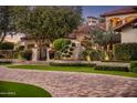 View of the front yard with brick driveway, lush lawn, mature trees, and an arched gate entrance to the property at 5902 E Arcadia Ln, Phoenix, AZ 85018