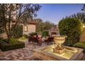 An outdoor patio area with a stone fireplace, comfortable seating, and a decorative fountain at 5902 E Arcadia Ln, Phoenix, AZ 85018
