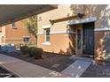 Condo front entry featuring neutral stucco, dark door, trimmed landscaping, and visible unit number '16' at 7726 E Baseline Rd # 156, Mesa, AZ 85209
